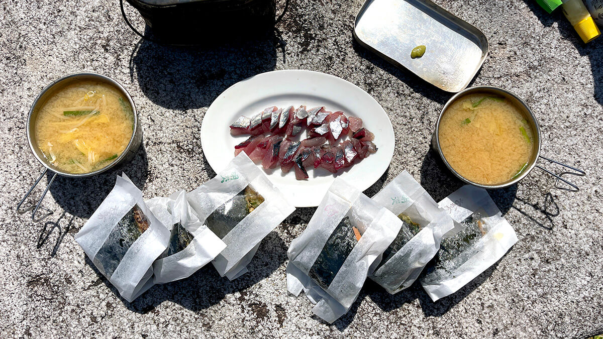 みかさのおにぎりとムロアジ刺身、あら汁を並べた新島2日目の釣り飯