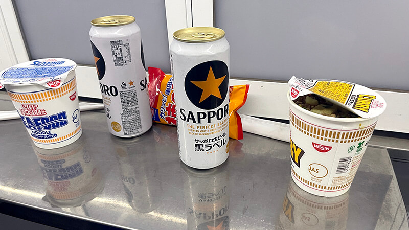缶ビールとカップヌードルを並べた出航後の簡単な夜食