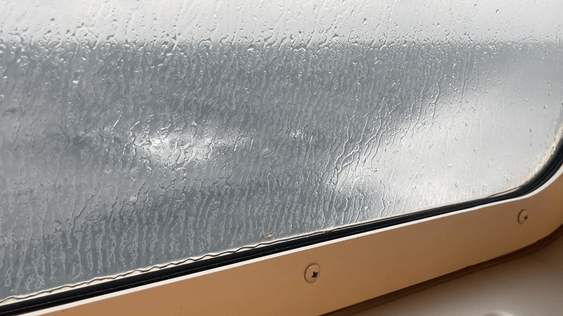 雨粒で白く曇る船窓の向こうにぼんやり見える海