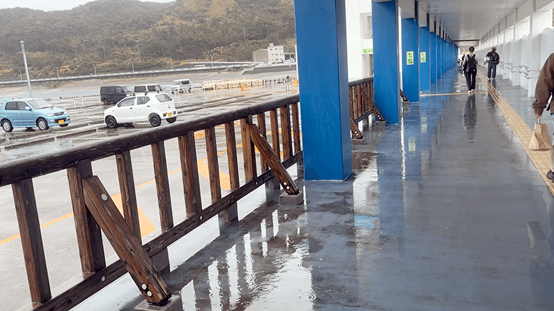 雨の新島港で下船後に歩く乗船客と濡れた通路