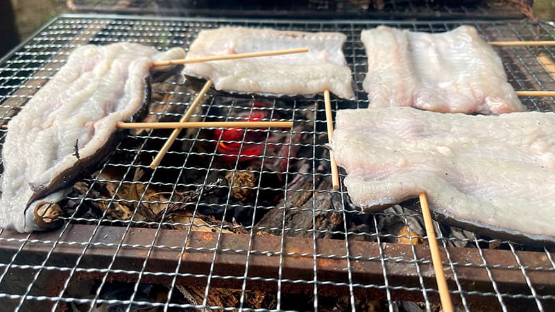 串を打ったウナギの身を炭火で素焼きする様子