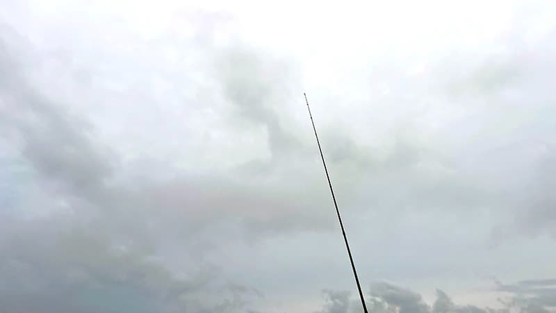 夏の日差しが強くなった汽水域の空と釣り竿