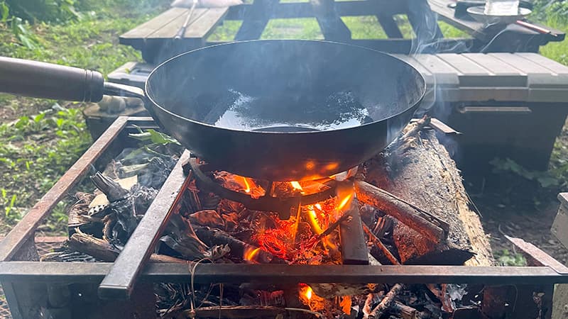 庭の焚き火で油を熱するおやじ中華鍋