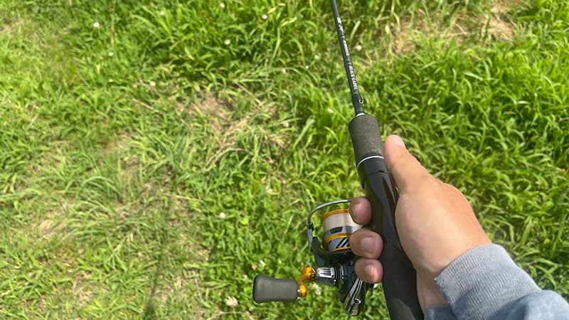 草の上で構えたダイワのライトロッドとスピニングリール