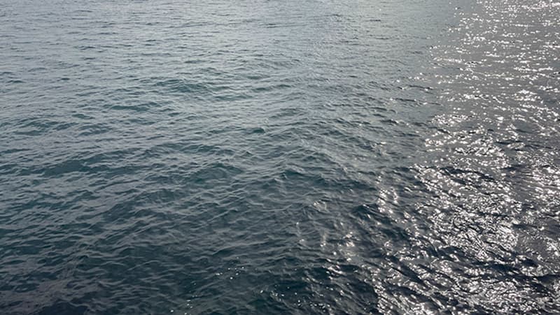光を反射して銀色に光る海面と、手前の濃い青の波