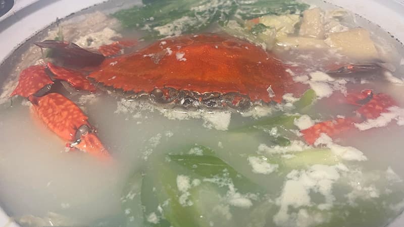 鍋の中で野菜や豆腐と一緒に煮えていく、赤くなったガザミ