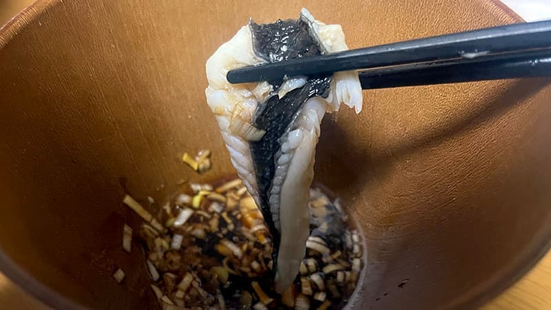 カニ出汁の鍋でしゃぶしゃぶした皮付きのグレを、肝ポン酢につけるところ