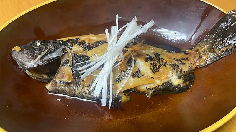 白髪ネギをのせたグレ(メジナ)の煮付け。飴色のたれが絡んでいる