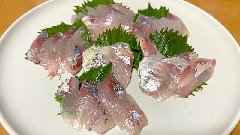 大葉を敷いた皿に盛った、銀皮を残したシマアジの刺身
